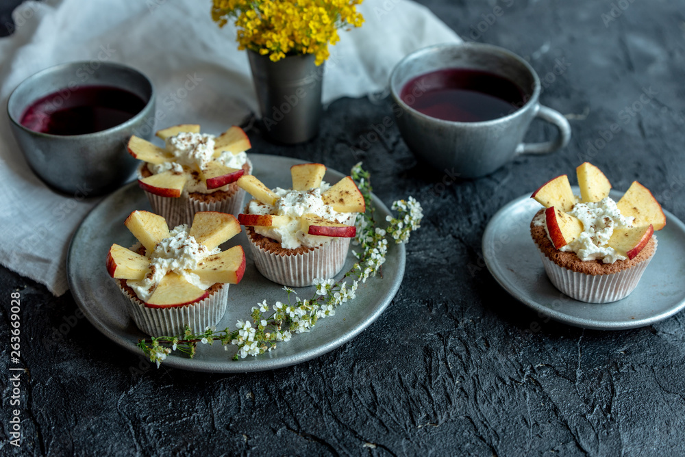 sweet muffins with yogurt and apples and tea on a dark, stone table