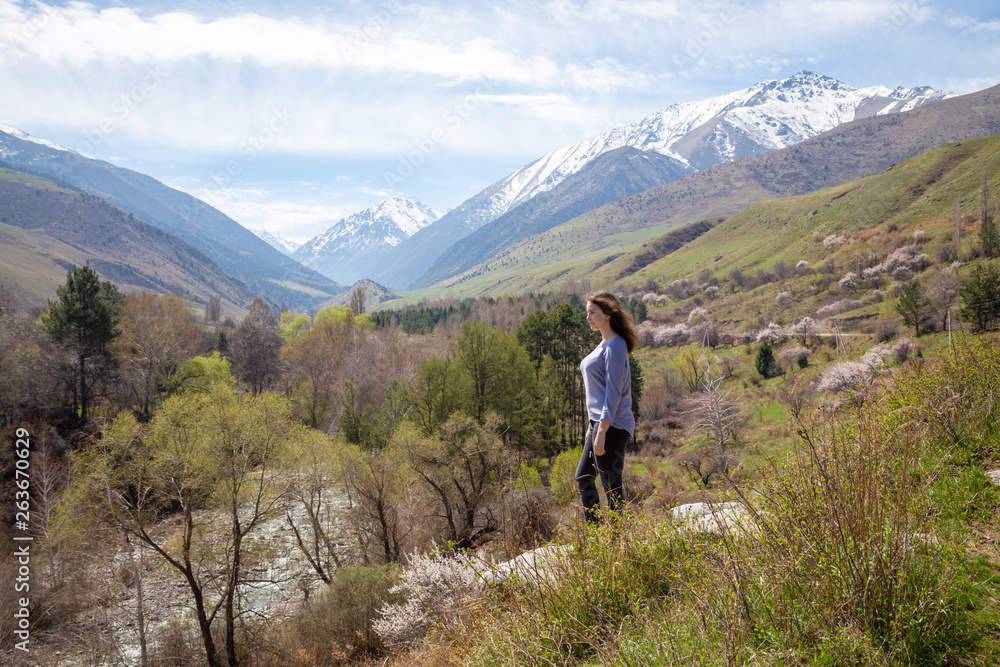 Young girl on the background of spring mountains. Beautiful mountain gorge. Nature and adventure.