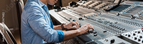 panoramic shot of mixed race sound producer working at mixing console in recording studio © LIGHTFIELD STUDIOS