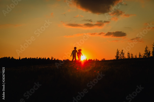 Silhouette of happy boy and girl run in sunset nature