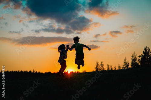 silhouette of happy boy and girl enjoy sunset nature © nadezhda1906