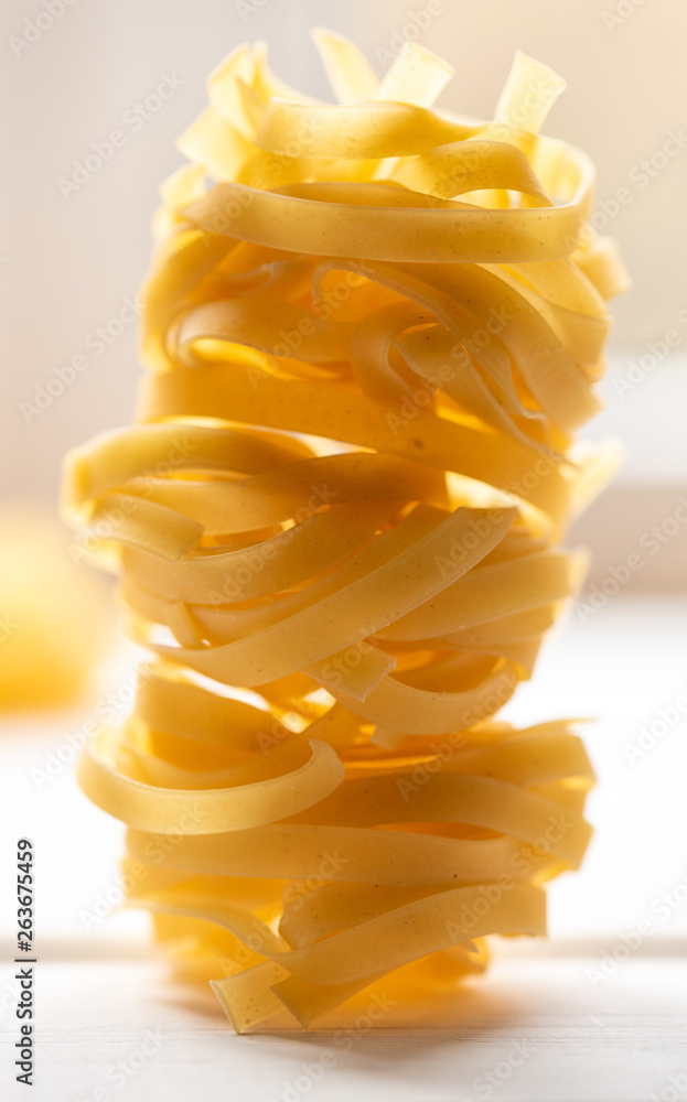 Dry uncooked fettuccine nest pasta on a light background. Dry uncooked fettuccine nest pasta on a light background.