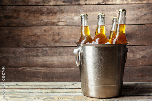 Cold bottles of beer in the bucket on the wooden background