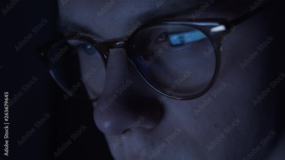Young nerd hacker mans face closeup with computer monitor reflecting in his glasses. Young nerd hacker mans face closeup with computer monitor reflecting in his glasses.