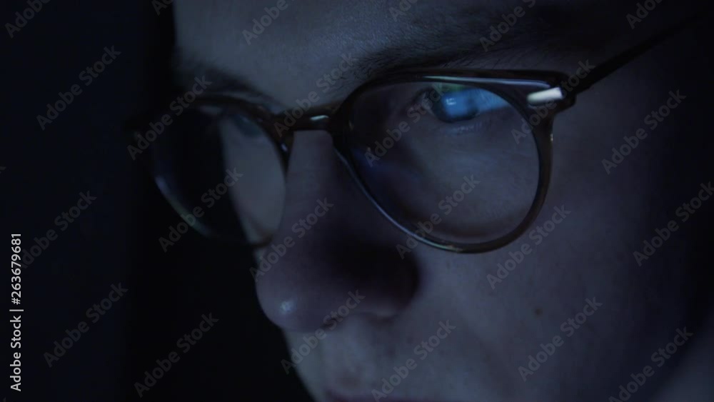 Very tired nerdy student with glasses is sitting in the darkness browsing the internet. Very tired nerdy student with glasses is sitting in the darkness browsing the internet.