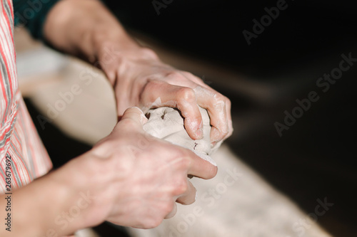 Close up of man works with clay. Male potter kneads and moistens the clay before work  toned