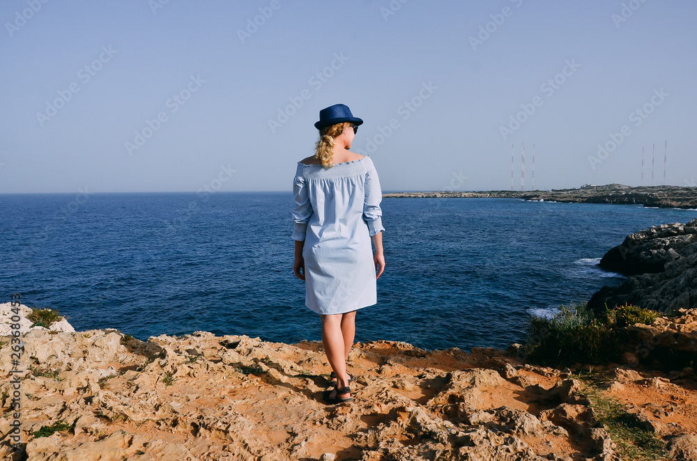 Beautiful young woman standing near sea. Woman on mountain in Cyprus, Mediterranean Sea