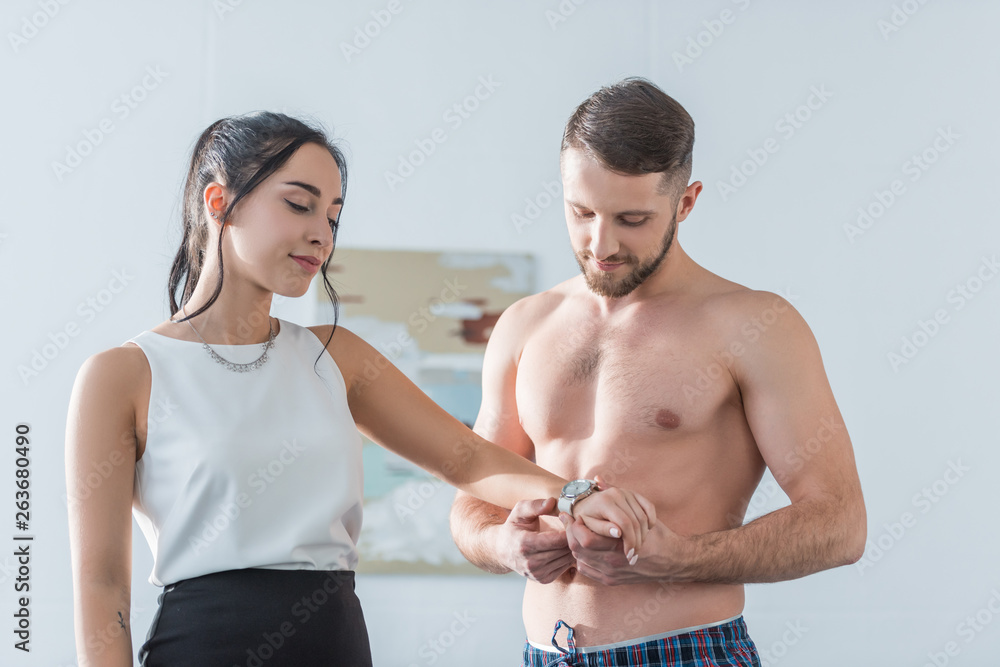 muscular bearded man wearing watch on hand of attractive brunette woman muscular bearded man wearing watch on hand of attractive brunette woman