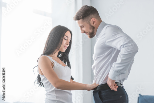 pretty brunette girl touching pants of bearded handsome man in white shirt