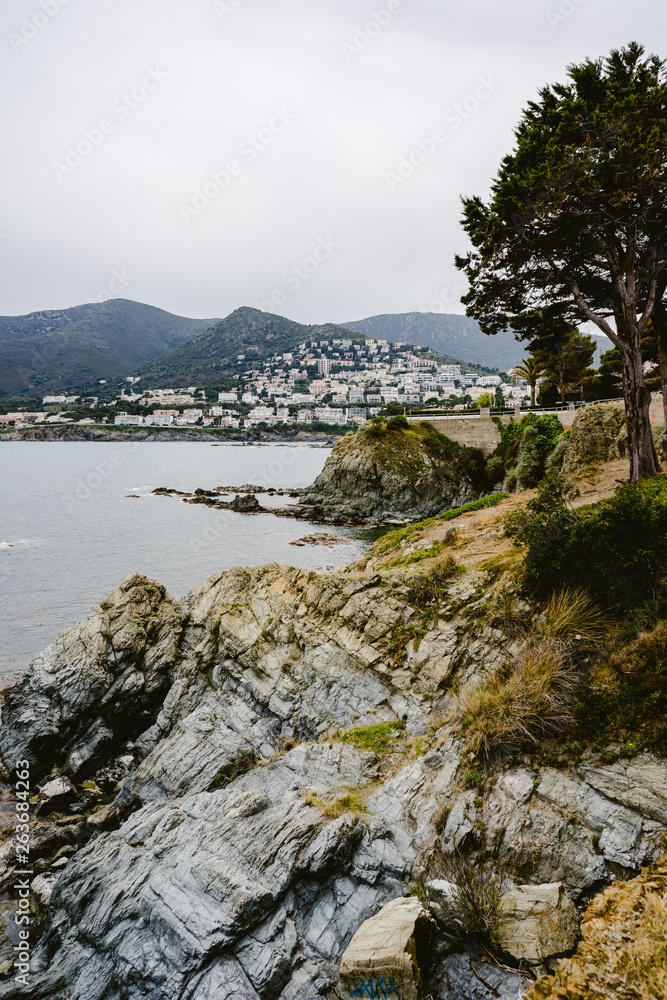 Coastal landscape with rocks and stones next to the beach, the sea and a coastal village with clear blue sky. Coastal landscape with rocks and stones next to the beach, the sea and a coastal village with clear blue sky.
