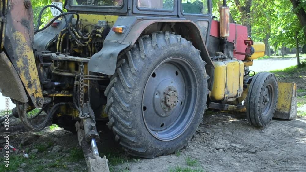 Tractor stands near ground pit. Backhoe piles up the ground close-up. Tractor stands near ground pit. Backhoe piles up the ground close-up.