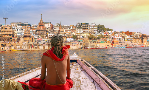 Varanasi city architecture with Ganges river bank at sunset with view of sadhu baba enjoying a boat ride on river Ganges. photo