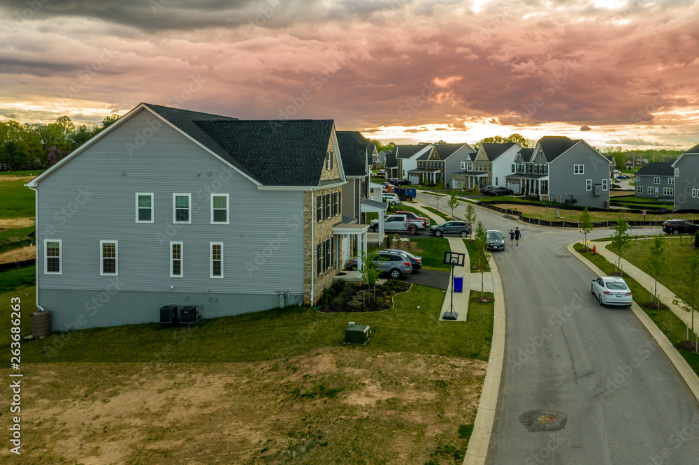 Aerial view of typical American new construction neighborhood street in Maryland for the upper middle class, single family homes USA real estate with dramatic sky Aerial view of typical American new construction neighborhood street in Maryland for the upper middle class, single family homes USA real estate with dramatic sky