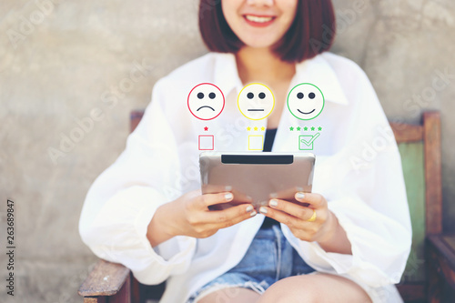 Woman hand holding tablet smart device with putting check mark with smiley face marker in coffee shop, Satisfaction evaluation and Customer experience concept photo