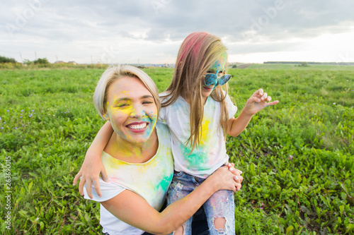 Happiness  Holi festival and holidays concept - two young women and girl having fun on holi festival