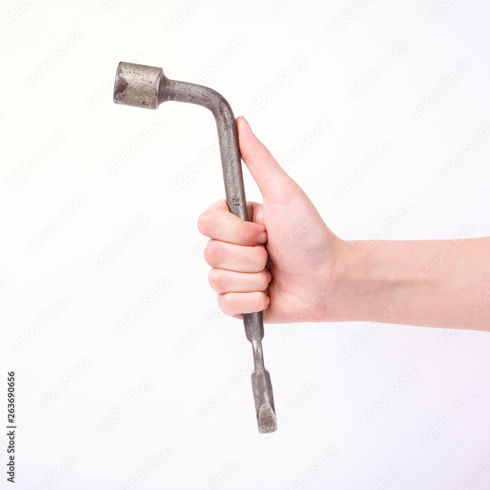 Wheel wrench in hand of the girl. Symbol of hard work, feminism and labor day. Isolate on white background. Wheel wrench in hand of the girl. Symbol of hard work, feminism and labor day. Isolate on white background.