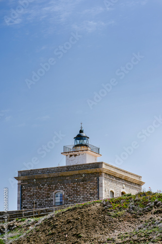 Lighthouse on a cloudless day with blue sky in coastal landscape on a summer day.