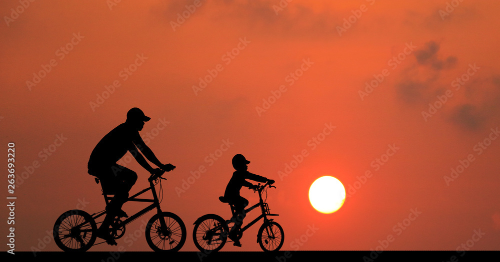 Fototapeta premium silhouette Father and son riding bicycle at sunset sky
