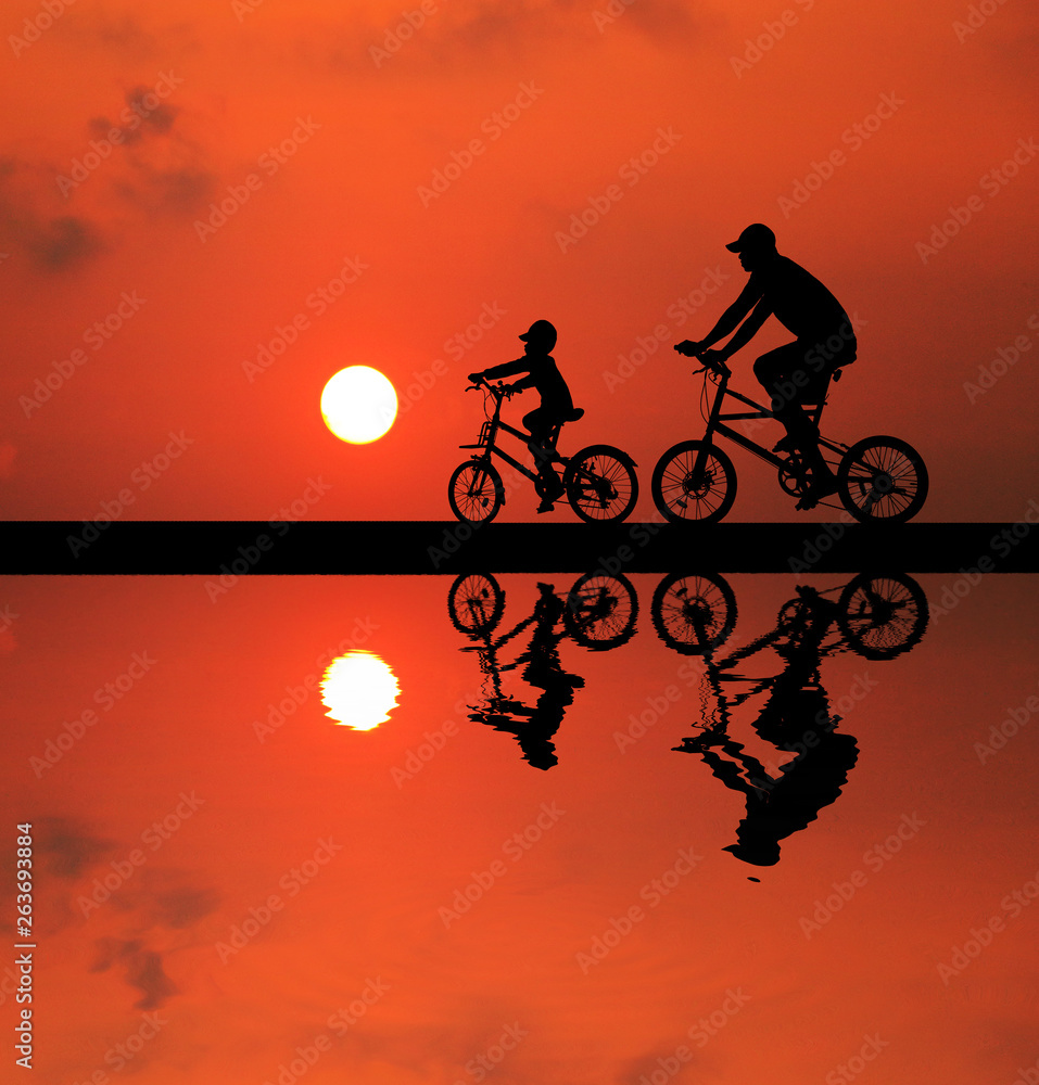 Obraz premium silhouette Father and son riding bicycle at sunset sky