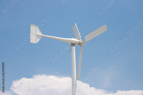 white wind turbine against blue sky with white cloud. concept: clean energy, resolve air pollution.