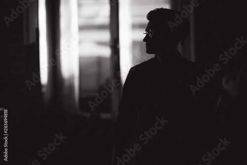 Silhouette of man in glasses inside. Backgroung of window