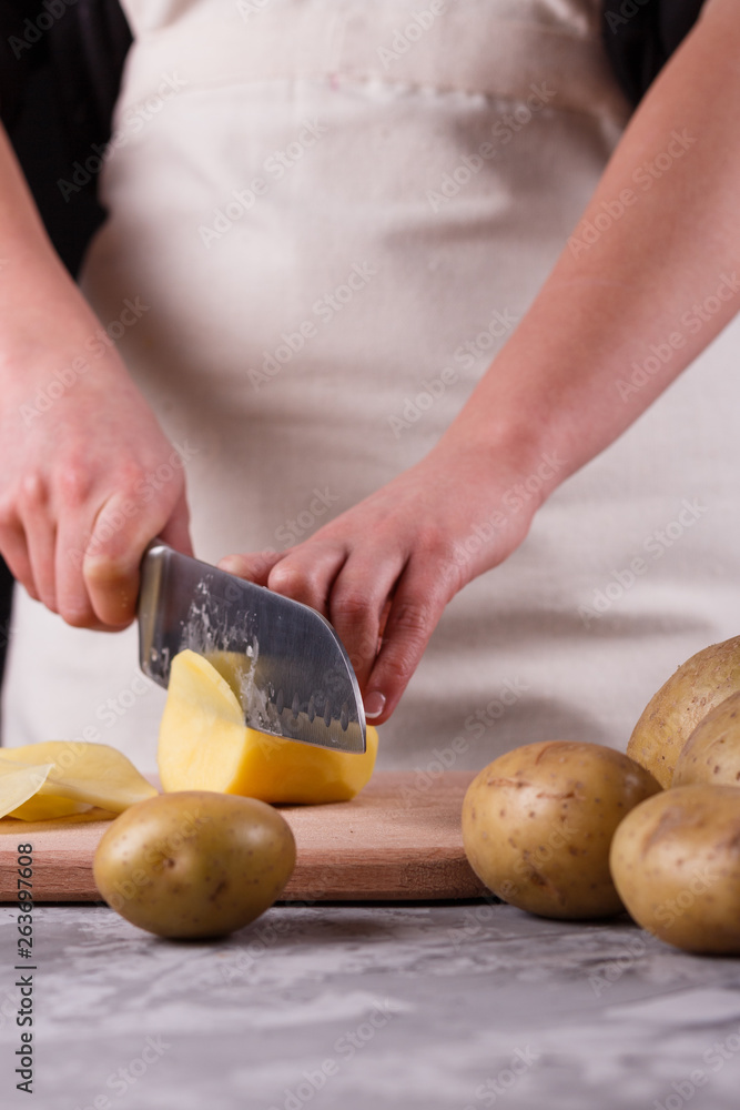 young woman in an apron cuts potatoes young woman in an apron cuts potatoes