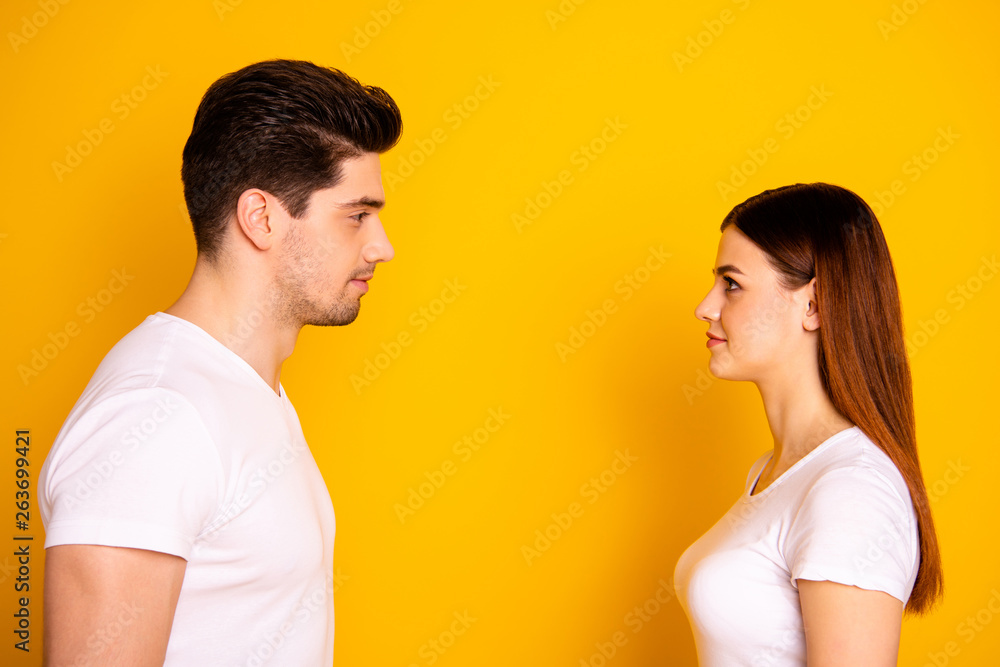 Close up side profile photo funny beautiful she her he him his guy lady stand opposite wait first who take eyes off each other lovely look wear casual white t-shirts outfit isolated yellow background Close up side profile photo funny beautiful she her he him his guy lady stand opposite wait first who take eyes off each other lovely look wear casual white t-shirts outfit isolated yellow background