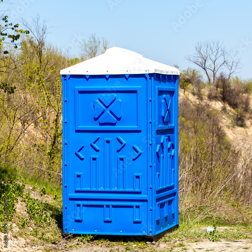 Blue Cabine Of Chemical Toilet In a Mountain Park at sunny Summer Day.