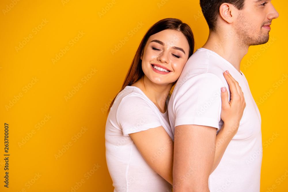 Close up side profile photo beautiful she her he him his guy lady pair hold tight close hands arms husband strong back eyes closed emotional wear casual white t-shirts isolated yellow background Close up side profile photo beautiful she her he him his guy lady pair hold tight close hands arms husband strong back eyes closed emotional wear casual white t-shirts isolated yellow background