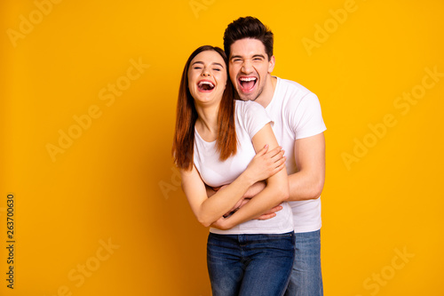 Portrait of his he her she two nice-looking lovely sweet attractive cheerful cheery positive people cuddling laughter isolated over vivid shine bright yellow background
