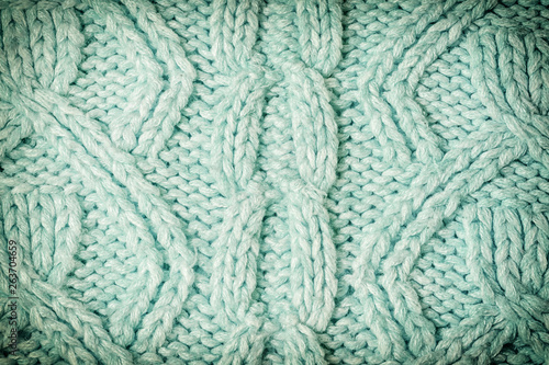 Knitted texture with patterns close-up. Blank turquoise background for layouts. Photo with vignette.