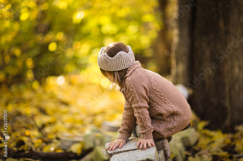 girl child plays in the forest in knitted tunic