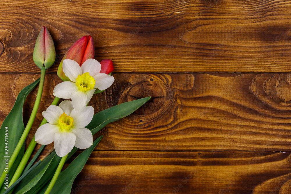 Bouquet of daffodils and red tulips on wooden background. Greeting card for Easter, Valentine's Day, Women's Day and Mother's Day. Top view, copy space Bouquet of daffodils and red tulips on wooden background. Greeting card for Easter, Valentine's Day, Women's Day and Mother's Day. Top view, copy space