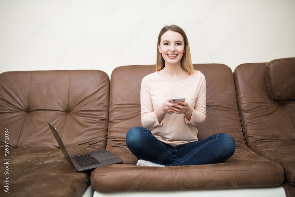 Pretty woman using typing on the phone and laptop at home in the living room Pretty woman using typing on the phone and laptop at home in the living room