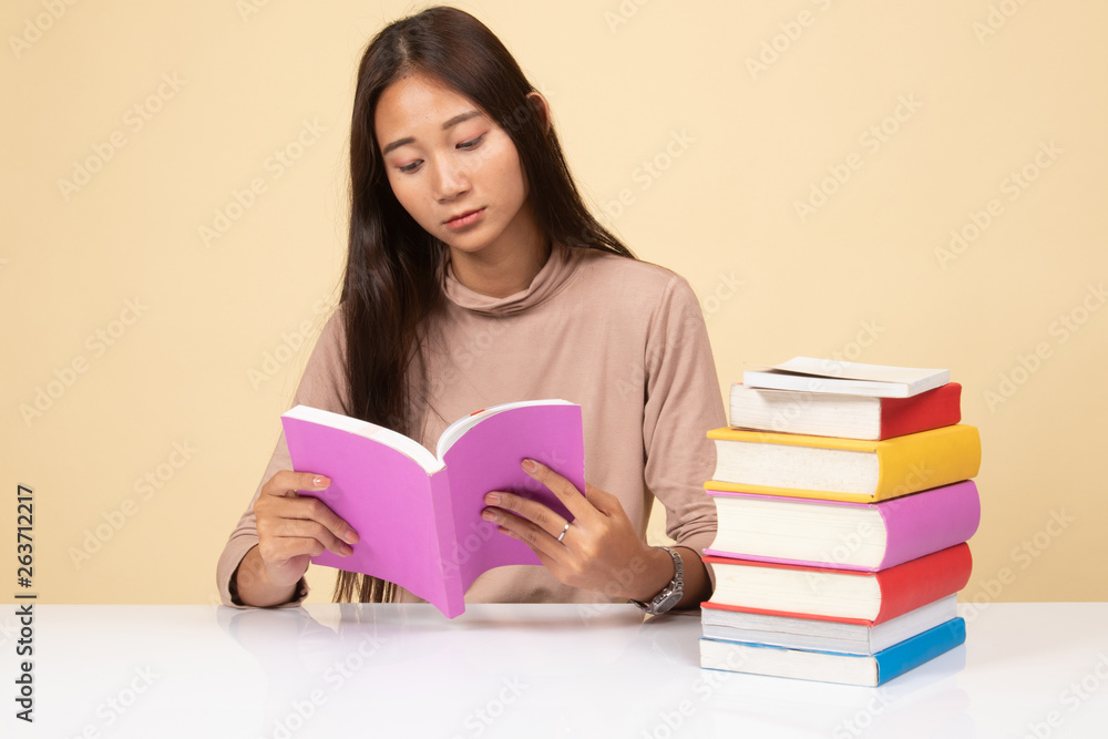 Young Asian woman read a book with books on table. Young Asian woman read a book with books on table.