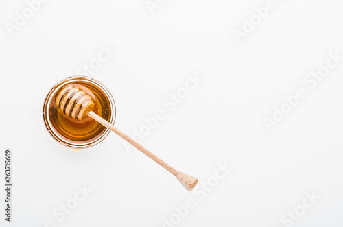Wooden honey dipper with honey in glass bowl