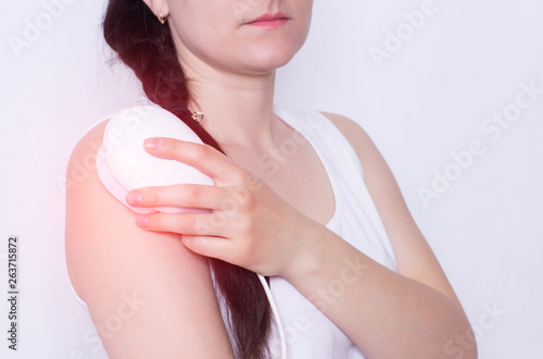 The girl treats a sore shoulder joint with the help of physiotherapy magnet, pain relief and inflammation, neck and chest