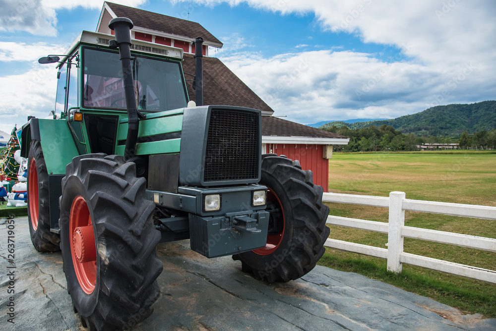 A retro tractor parked next to a barn in a farm.Thailand. A retro tractor parked next to a barn in a farm.Thailand.