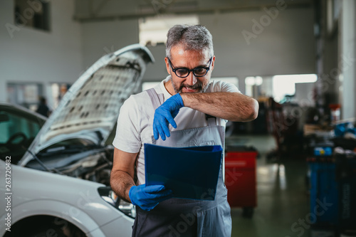 worker checking part list in car service