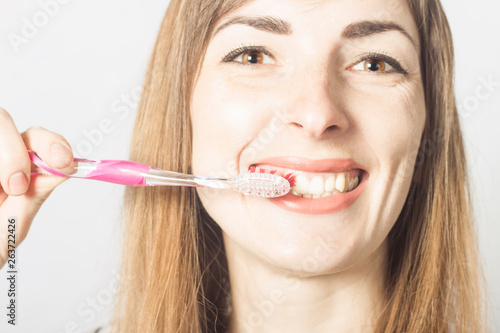 A young girl brushes her teeth on a light background. Oral care concept, personal hygiene, dentistry.
