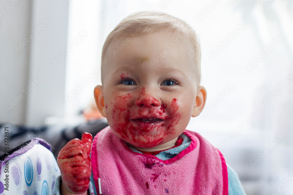 A small child eats fresh berries and smeared his face. Very funny image. A small child eats fresh berries and smeared his face. Very funny image.