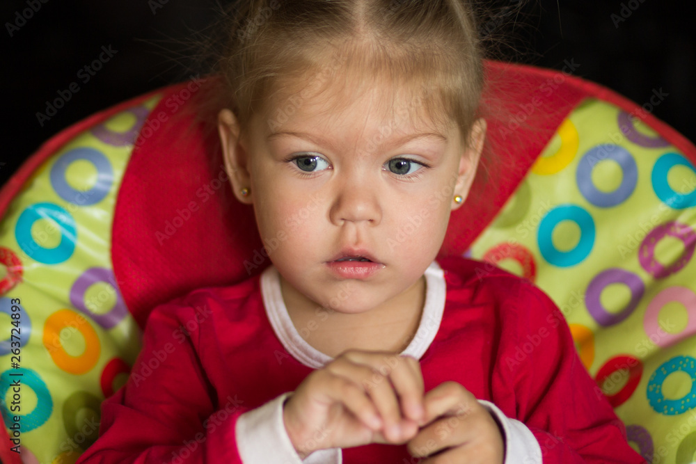 portrait of little girl with pensive look sitting in the feeding chair looking aside portrait of little girl with pensive look sitting in the feeding chair looking aside