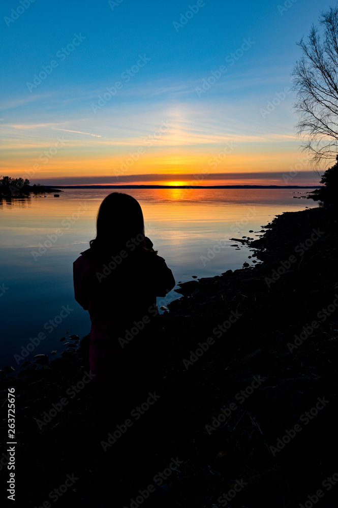 siluette of a young person standing infront of a sunrise