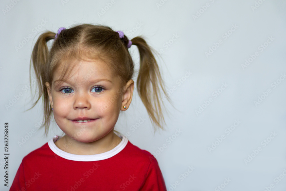 Portrait of little girl with blue eyes biting lower lip looking at camera on the white background Portrait of little girl with blue eyes biting lower lip looking at camera on the white background