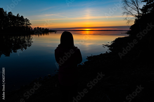 siluette of a young person standing infront of a sunrise