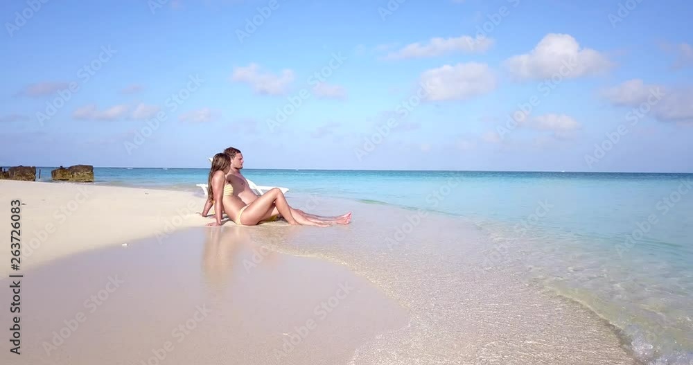 Man and woman sitting in calm waves looking out of Maldives ocean Man and woman sitting in calm waves looking out of Maldives ocean