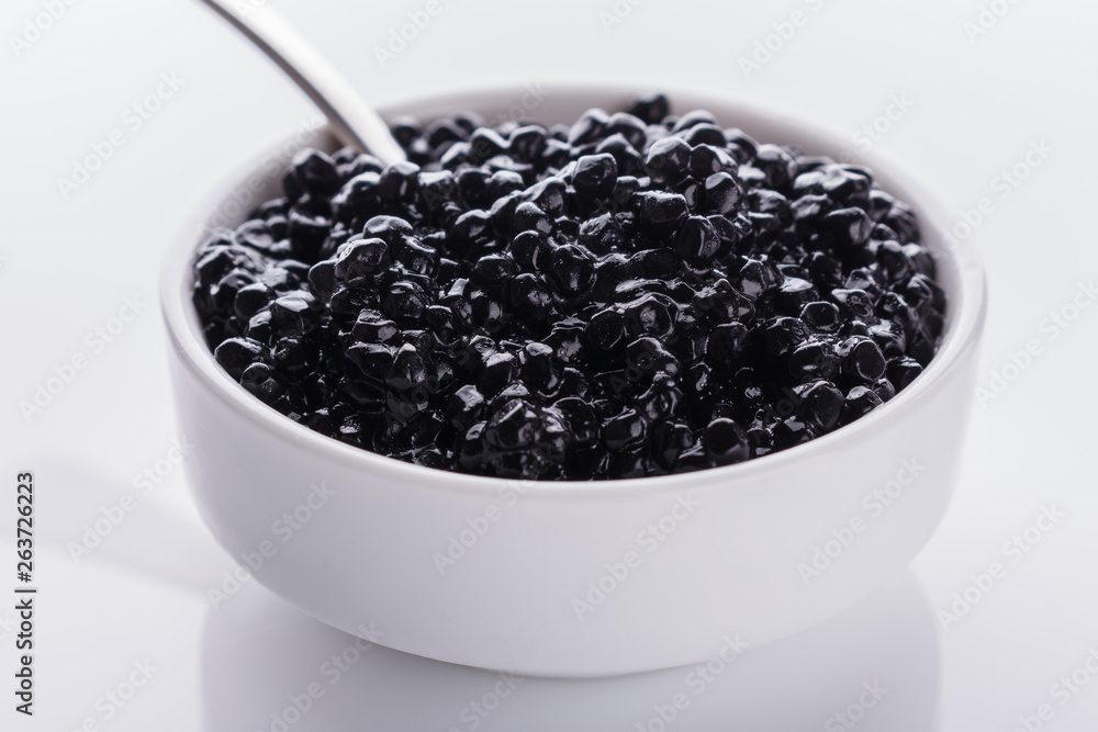 black caviar in a bowl on a white acrylic background black caviar in a bowl on a white acrylic background