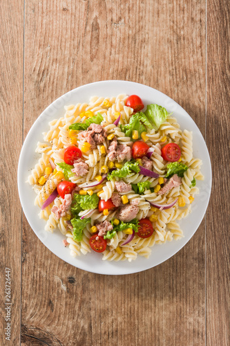 Pasta salad with vegetables and tuna on wooden table. Top view