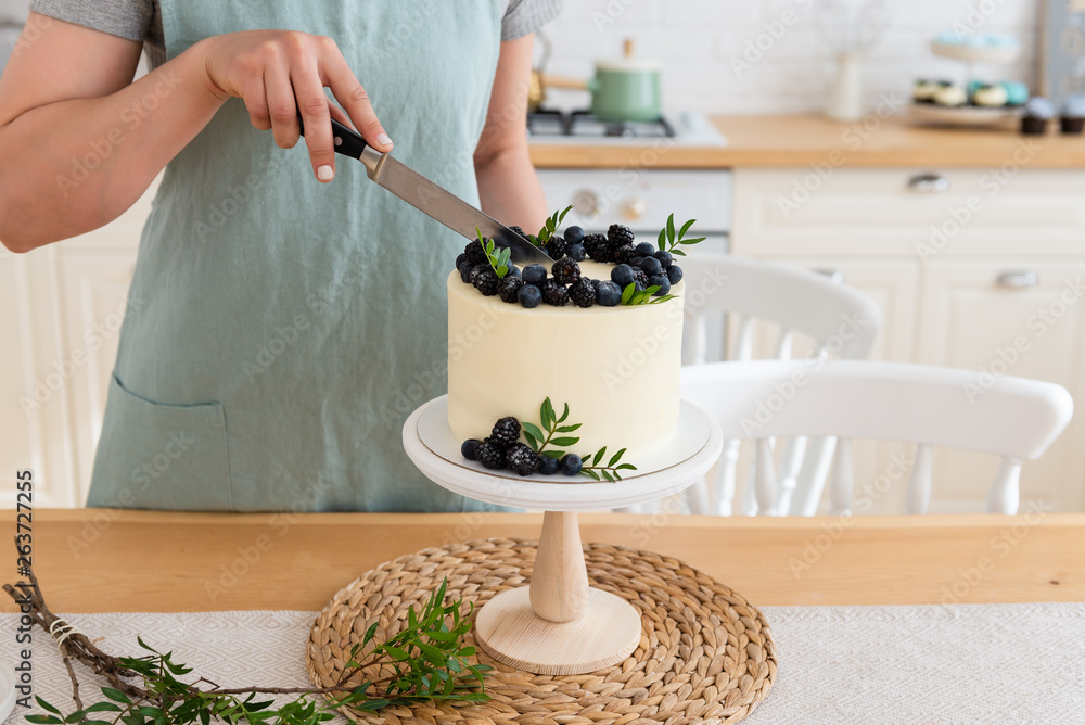 Women cutting birthday cake with berries. Close up. White cake with cream cheese and fresh blueberries and blackberries. Close up, copy space. Confectionery banner
