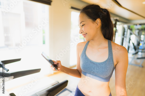Portrait beautiful asian young woman using mobile phone in gym